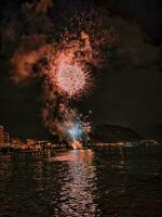 colorato fuochi d'artificio nel il notte cielo su il lungomare di alicante Spagna foto