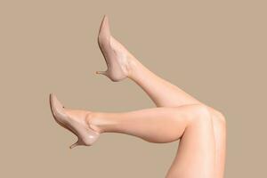 womans gambe nel beige brevetto pelle scarpe Ciao tacchi isolato su beige nudo sfondo foto