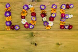 Immagine di parola amore fatto di bellissimo fiori su di legno sfondo foto