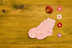 poco rosa bambino ragazza calzini con pacificatore e fiori su di legno tavolo.bambino annuncio concetto. foto