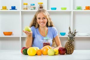 bellissimo ragazza è mostrando Mela e frutta frullato foto