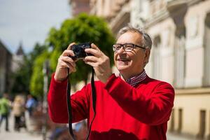 anziano uomo turista gode Fotografare a il città foto