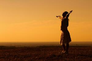 silhouette di poco ragazza saluto il tramonto foto