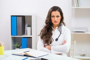 arrabbiato femmina medico guardare a documenti mentre Lavorando a sua ufficio foto