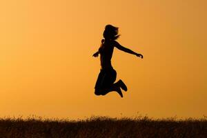 silhouette di contento donna salto nel il natura foto