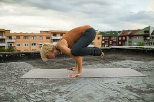 donna praticante yoga su il tetto foto