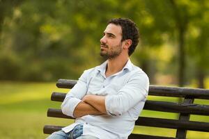 preoccupato uomo d'affari è seduta a il parco e pensiero di qualcosa foto