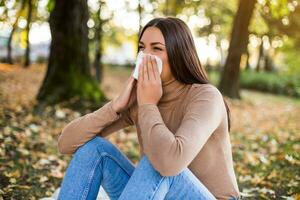 donna soffiaggio naso mentre seduta nel il parco foto