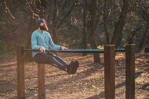 uomo gode esercizio spingere UPS su parallelo barre nel il parco. foto