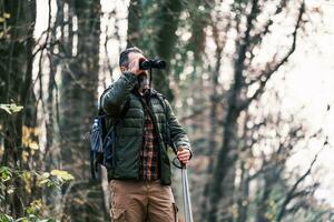 Immagine di uomo escursioni a piedi e utilizzando binocolo foto