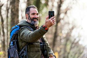 Immagine di uomo gode escursioni a piedi e fabbricazione autoscatto con il suo Telefono foto