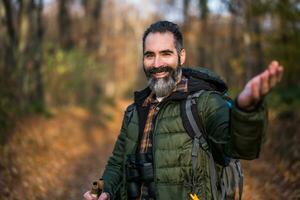 Immagine di escursionista mostrando invito gesto mentre escursioni a piedi nel natura foto