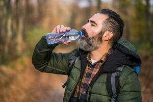 Immagine di uomo potabile acqua mentre escursioni a piedi foto