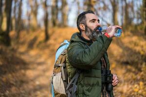 Immagine di uomo potabile acqua mentre escursioni a piedi foto