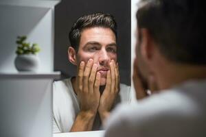 uomo guardare il suo occhio borse nel specchio foto