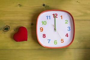 Immagine di orologio mostrando mezzanotte e cuore su di legno tavolo foto