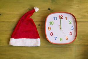 Immagine di Santa cappello e orologio mostrando mezzanotte su di legno tavolo foto