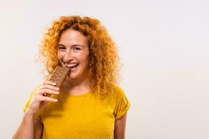 ritratto di contento carino Zenzero donna gode mangiare cioccolato foto