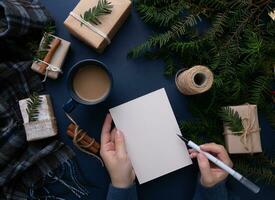 mani un' ragazza scrittura un' Natale elenco su un' blu sfondo nelle vicinanze è un' tazza di caffè e i regali foto