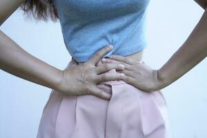 asiatico donna dire bugie con stomaco dolore a partire dal irregolare mestruazione foto