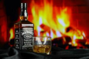 kiev, Ucraina - Maggio 4, 2022 Jack daniel originale alcool bottiglia su di legno tavolo con rosso camino foto