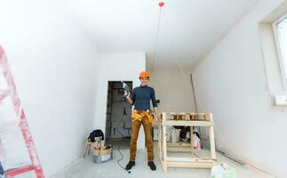 costruttore raccoglie il pezzi di pavimento piastrelle in un' bianca Borsa nel un' piccolo camera vicino su foto