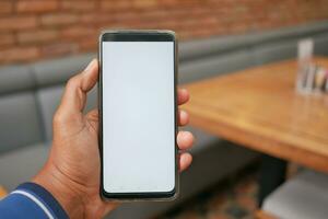 giovane uomo mano utilizzando inteligente Telefono con bianca schermo a bar foto