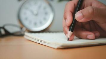 umano mani scrittura Appunti con matita su carta su di legno tavolo superficie. foto