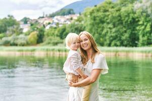 all'aperto ritratto di contento giovane madre con adorabile bambino in età prescolare figlio, godendo simpatico giorno Il prossimo per lago foto