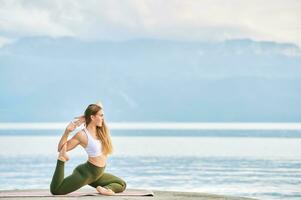 all'aperto ritratto di giovane bellissimo donna praticante yoga di il lago foto