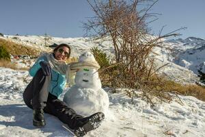 latino donna seduta su congelato terra Il prossimo per pupazzo di neve foto