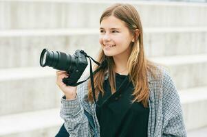 all'aperto ritratto di giovane contento adolescenziale ragazza Tenere mirrorless telecamera foto