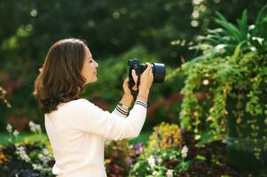 all'aperto ritratto di bellissimo donna assunzione immagini con mirrorless telecamera nel verde giardino foto