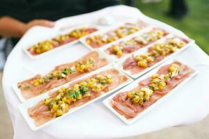 Cameriere Tenere vassoio con tonno carpaccio servito con Mango e verde erbe aromatiche, ristorazione per eventi foto