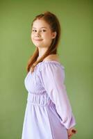 bellezza ritratto di bella giovane 15 - 16 anno vecchio dai capelli rossi adolescente ragazza indossare viola vestito in posa su verde sfondo foto