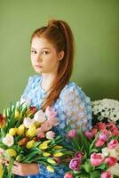 ritratto di bella giovane 15 - 16 anno vecchio dai capelli rossi ragazza circondato di molti primavera fiori in posa su verde sfondo, bellezza e moda concetto foto