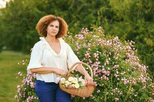 all'aperto ritratto di bellissimo 50 anno vecchio donna godendo simpatico giorno nel fiore parco o giardino, contento e salutare stile di vita foto