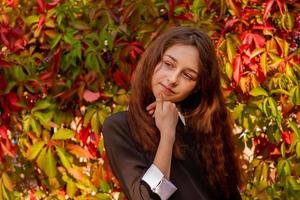 studentessa in abiti scolastici in natura su uno sfondo di foglie d'autunno. ragazza di 11 anni. foto
