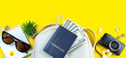 concetto di viaggio estivo. passaporto, denaro, occhiali da sole e una macchina fotografica su sfondo giallo. formato banner