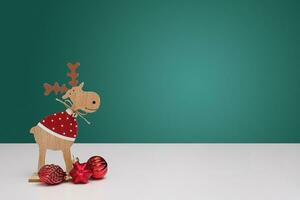un' di legno Natale renna con palle sta su un' bianca tavolo su un' sfocato bokeh sfondo. il sfondo è verde. foto