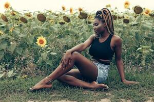 africano americano ragazza nel un' campo di giallo fiori a tramonto foto