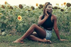 africano americano ragazza nel un' campo di giallo fiori a tramonto foto