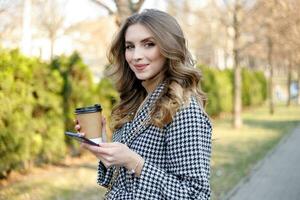 donna nel trincea cappotto a piedi e potabile caffè a partire dal carta tazza foto