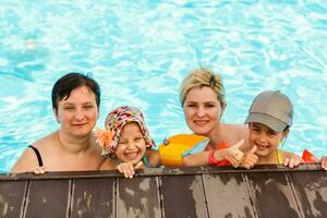 Due donne e loro bambini nel il piscina foto