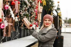 ragazza Selezione decorazione su un' tradizionale Natale mercato foto