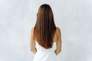 bellezza e cura dei capelli. vista posteriore della giovane signora bruna sensuale con capelli voluminosi in posa isolato su bianco e mostrando i suoi capelli sani. foto d'archivio