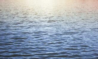 blu acqua sfondo. il tramonto è riflessa nel il mare. onde foto