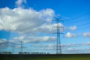 energia trasmissione Linee nel il campo. alto voltaggio energia trasmissione torri foto