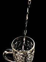 estetico foto di scrosciante acqua in un' bicchiere con nero sfondo