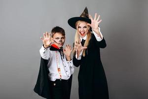 madre e figlio in costume che mostra gesto spaventoso alla telecamera.- halloween concept foto